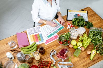 A woman is making personalized food charts with fruits and vegetables in front of her.