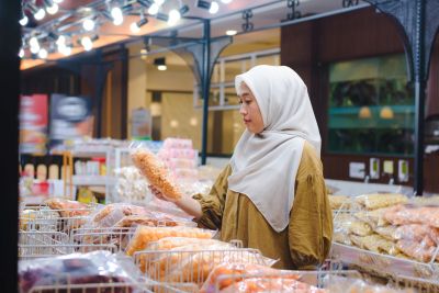Asian Muslim Woman Shopping for Local Snacks in Modern Market.