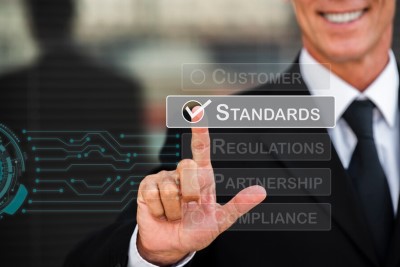 A smiling man touching the word 'standards' on a mirror display.