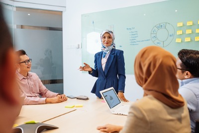 Mature muslim businesswoman with hijab having presentation in front of diverse colleagues.