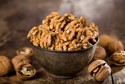 A handful of walnuts served in a black bowl.