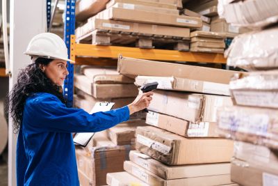 A woman checking her warehouse inventory using RFID and GPS technology with her hand held machine.