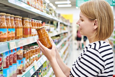 A white woman looking for emulsifiers in the list of ingredients before she buys the product from supermarket.